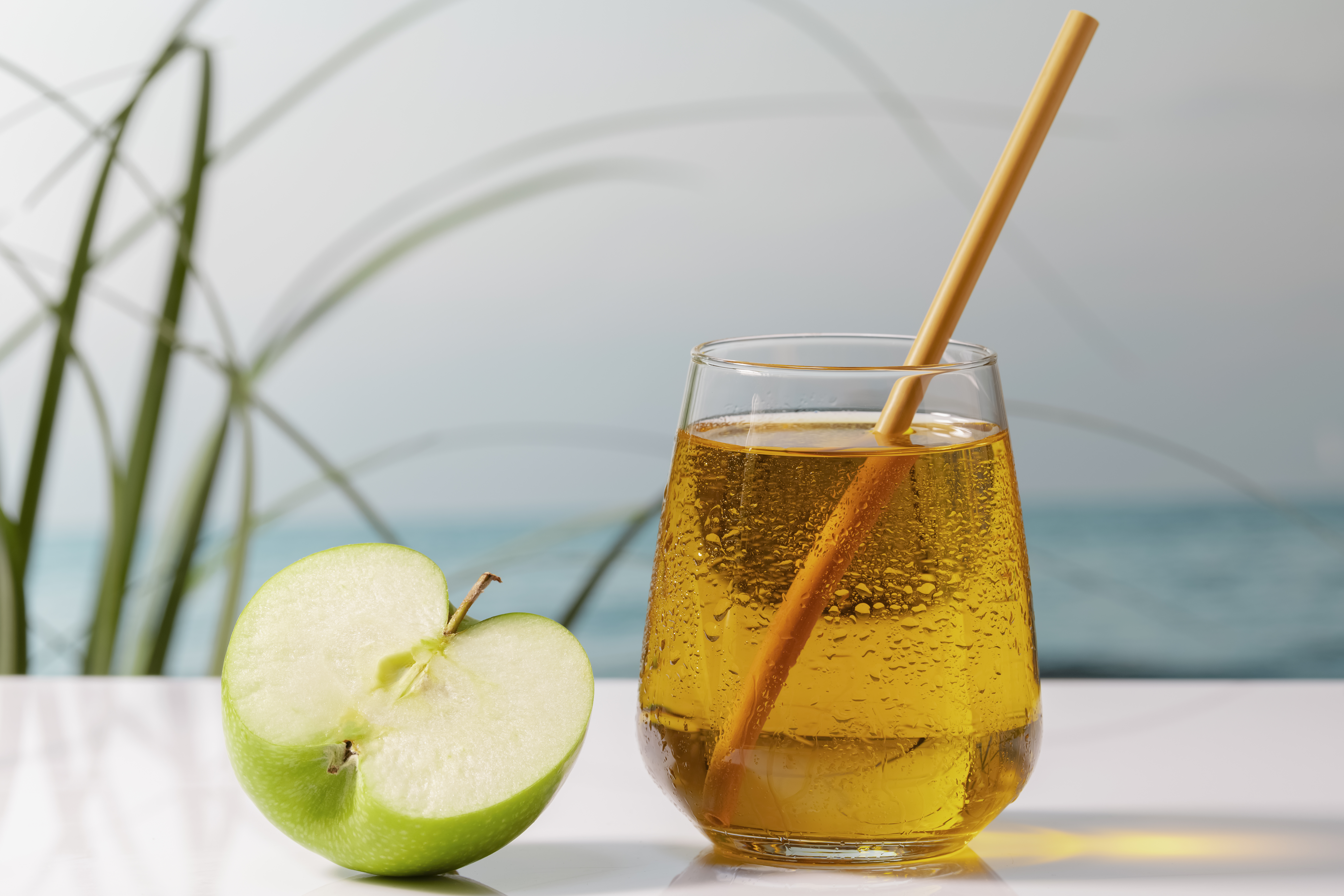 a glass of apple juice next to an apple cut in half for a 2021 fall flavor trend image
