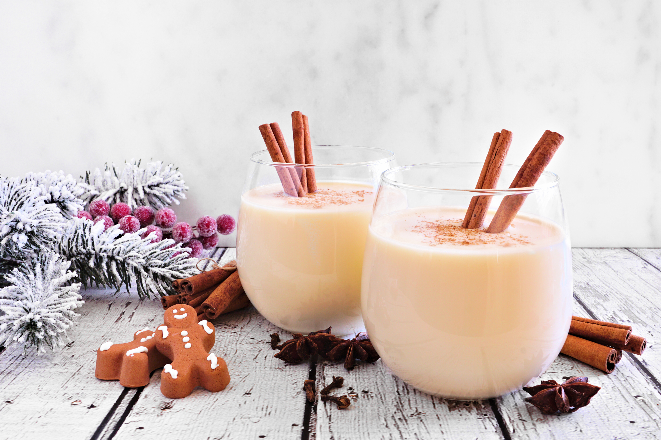 Winter 2022 Flavor trend Spiced Christmas eggnog with gingerbread men and holiday decor against a white background